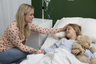 In a hospital, a caring mother comforts her sick daughter, showing unwavering support and affection