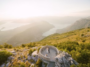 Bride and groom standing on the observation deck on the mountain against the backdrop of the Bay of