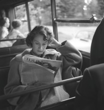 Woman in the 1950s. A young woman on a bus ride spends her time reading a magazine. Sweden 1952.