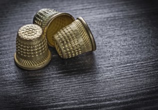 Metal thimbles on wooden board fancy-work concept