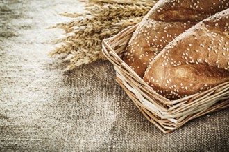 Wicker basket bread rye ears on burlap background