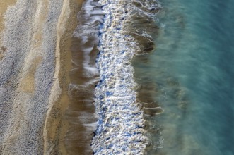 Aerial view of stormy ocean waves breaking on a sandy beach. Nature background