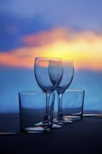 Dish of cups and crystal transparent glasses on a sea sunset table