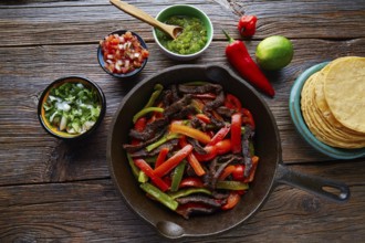 Beef fajitas in a pan with sauces chili and sides Mexican food