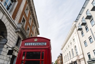 Traditional red telephone box in London, England, UK. Low angle view against sky in Covent Garden