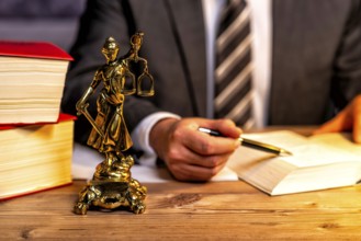 Office of a lawyer with books and a statue of Lady Justice, goddess Justitia, on the desk