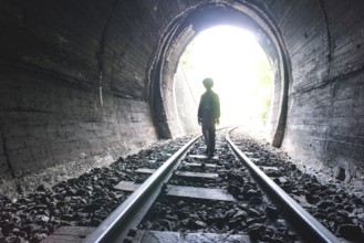 Child walking in railway tunnel. Vintage clothes