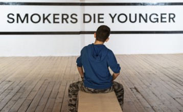 Teenager smoking and message on wall - Smokers die younger. No smoking concept with child. Casual