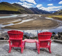 Multi-colored mountains from mineral rhyolite are lit with sun. Two red chaise lounges stand for