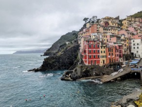 A picturesque seaside village with vibrant houses on cliffs beside a choppy ocean. Cinque Terre,