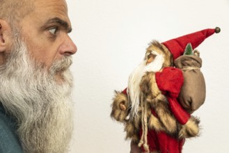 An image of a bearded man looking to a Santa Claus puppet