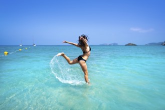 Ibiza beach girl splashing water jump in Balearic islands