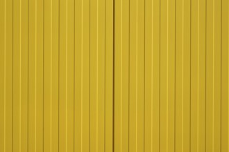 The close-up of a colourful and bright yellow corrugated metal wall of a shopping centre