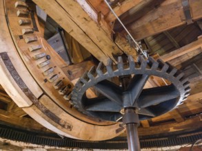 Large cogwheels within an old wooden structure, industrial mechanics visible