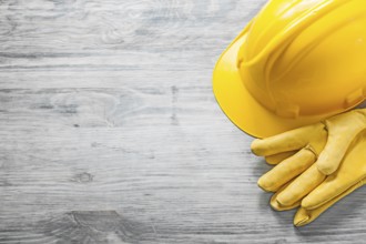 Yellow hard hat protective gloves on wooden board copy space construction concept