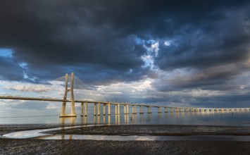 Vasco da Gama Bridge at sunset with dramatic cloudy blue sky in Lisbon, Portugal, Europe