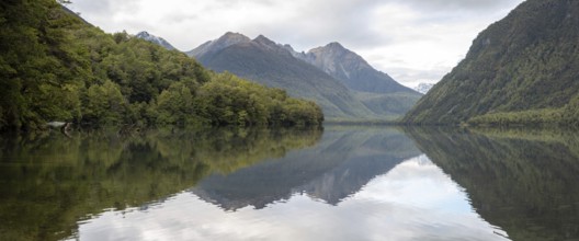 Tranquil lake Gunn in Fiordland National Park, landscape reflecting on the water surface, South