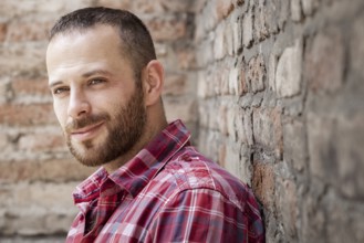 An image of a bearded man at the brick wall