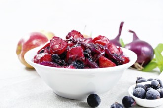 Chutney of apple, red onion and blackcurrant in a bowl against a granite countertop