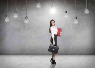 Business woman stnads in a gray room with hanging bulbs