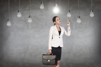 Business woman stands in a gray room with hanging bulbs