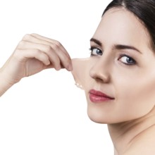 Beautiful woman remove her old dry skin from face. Over gray background