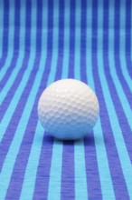 White golf ball on blue striped tablecloth
