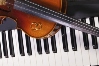Detail of piano keyboard, old violin and wedding rings