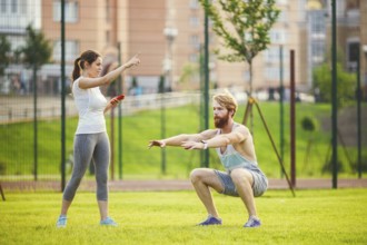 Team work in sports. female trainer training man with beard in park on green grass, lawn at sunset.