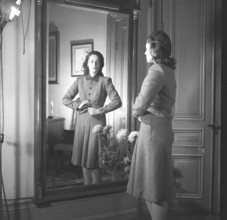 Actress Viveca Lindfors, 1920-1995. She stands in front of the mirror and buttons the last button
