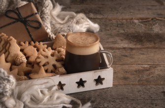 Christmas breakfast table with a tray full of gingerbread cookies, a cup of coffee, a wool scarf,