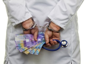 A doctor with Swiss franc banknotes and handcuffs Austria