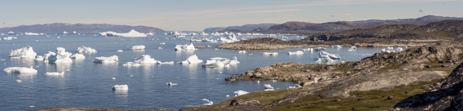 A breathtaking coastal landscape near Ilulissat, Greenland, featuring the Arctic Ocean dotted with