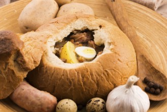 Traditional white borscht (zurek) with sausage, egg and mushrooms in bread as bowl