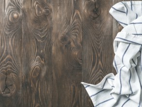 View from above on brown wooden table with linen kitchen towel or textile napkin. Blue tablecloth
