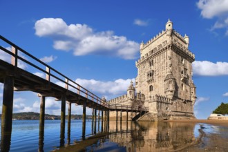 Belem tower and wooden bridge to it, Lisbon, Portugal at blue summer day sky with clouds. Medieval