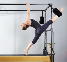 Pilates woman in cadillac split legs stretch exercise at gym