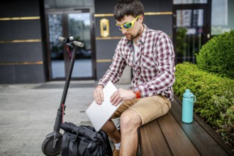 Young caucasian man in casual clothes freelancer uses eco-friendly electric transport scooter. Male