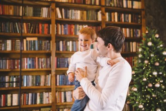 Happy young father and son have fun playing at home near Christmas tree. New Year and Christmas
