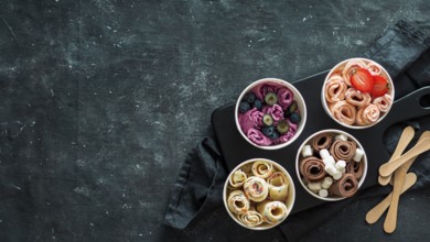 Rolled ice cream in cone cups on dark background. Different iced rolls top view or flat lay. Thai