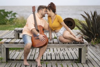 Couple of musicians sitting on the beach about to kiss