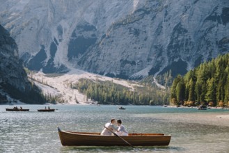 Bride and groom sail in a wooden boat at the Lago di Braies in Italy. Wedding in Europe, on Braies