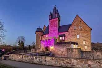 An illuminated castle at night, its walls glowing in pink light, Spangenberg Castle