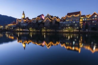 Christmas illuminated house facade of Frohnleiten reflected in the river Mur, blue hour,