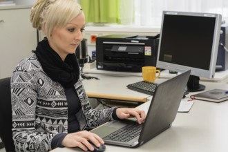 Young office clerk works in the office at a computer workstation