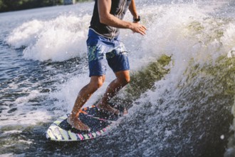 Active wakesurfer jumping on wake board down the river waves. Surfer on wave. Male athlete training