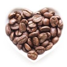 Black coffee beans in the heart shape bowl on a white
