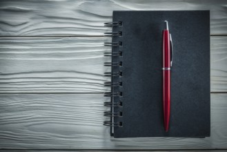 Black notepad pen on a white wooden board