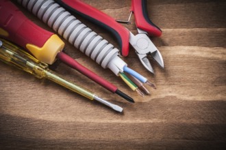 Nippers insulated screwdrivers corrugated pipe on wooden board