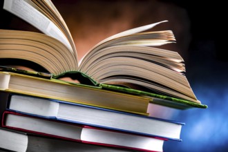 A composition with an open book lying on a stack of other books